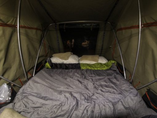 Barraca de teto armada e arrumada com travesseiros e saco de dormir