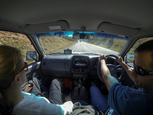 Foto de dentro do carro que mostra uma estrada asfaltada e pista simples.