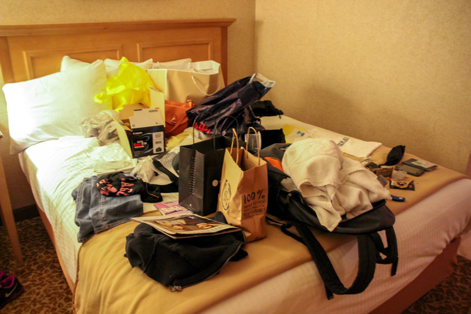 Viajar com amigos - Cama de casal de hotel em Las Vegas cheia de sacolas de compra, caixas, mochila e toalha de banho